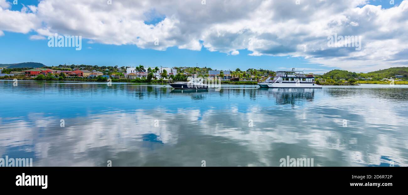 Green Bay of St John`s, Antigua and Barbuda. Panoramic view of the harbour bay with boats and reflection of the clouds in the water. Stock Photo